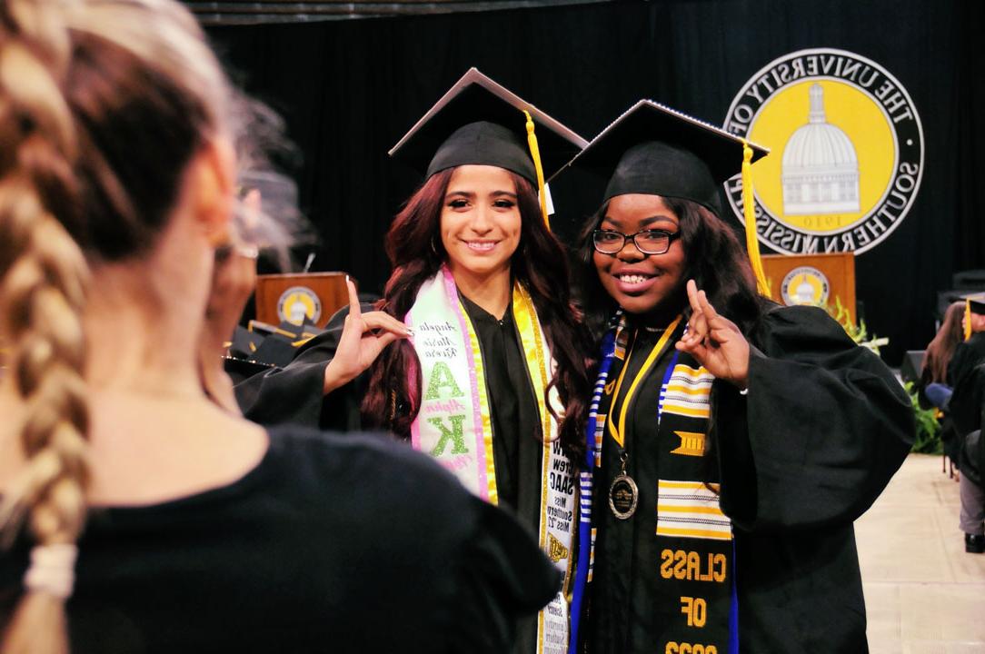 Graduates smile while waiting to recieve their diplomas